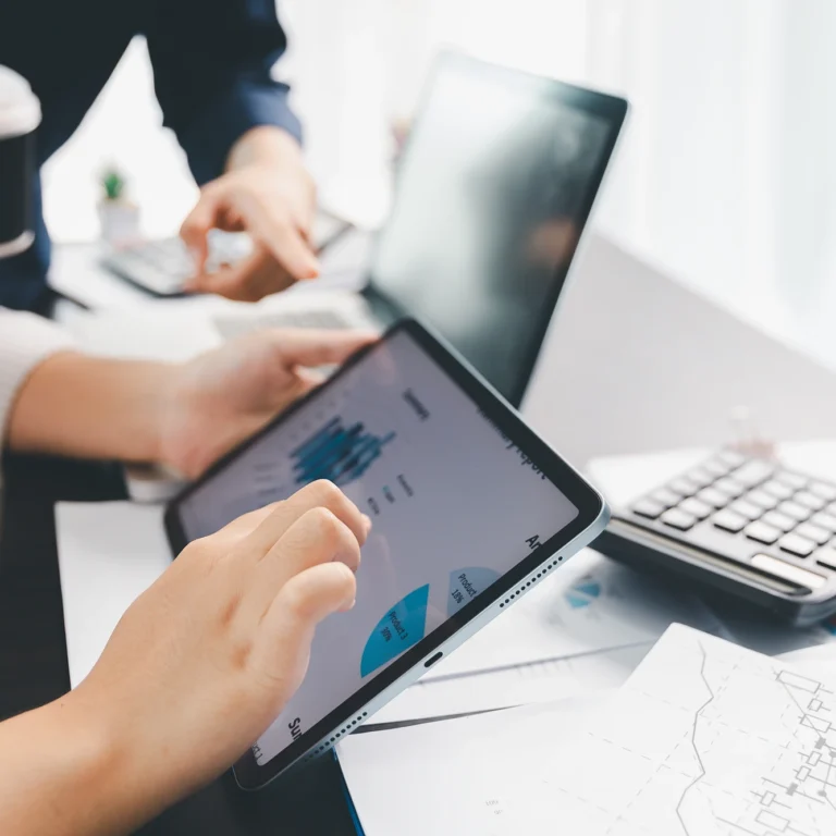 Business professionals collaborating on a tablet, discussing ideas and strategies in a modern office setting.