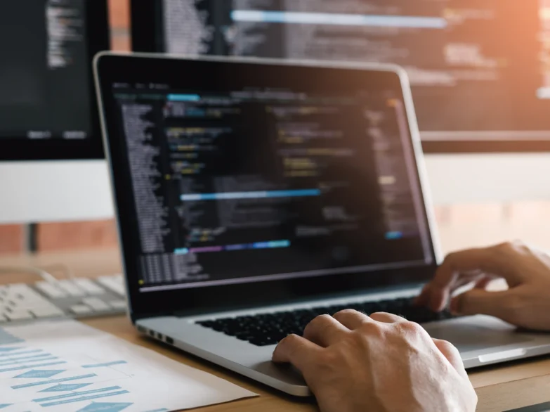A person focused on typing on a laptop computer, with hands on the keyboard.