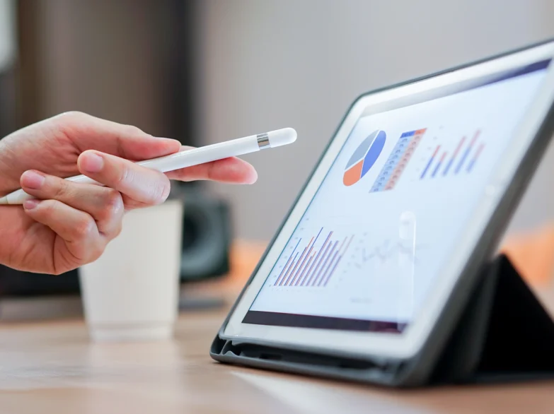 A person holds a pen and points at a tablet screen, engaged in a discussion or presentation.